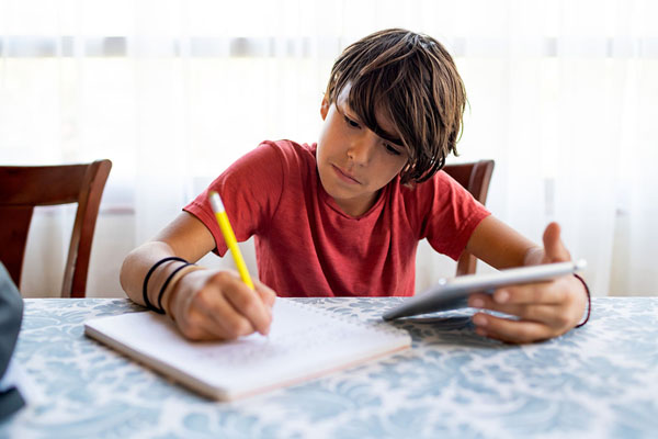 latinx preadolescent boy doing homework with a digital tablet