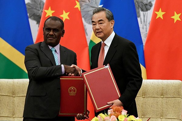 Chinese State Councilor and Foreign Minister Wang Yi shakes hands with Solomon Islands Foreign Minister Jeremiah Manele during a ceremony in Beijing