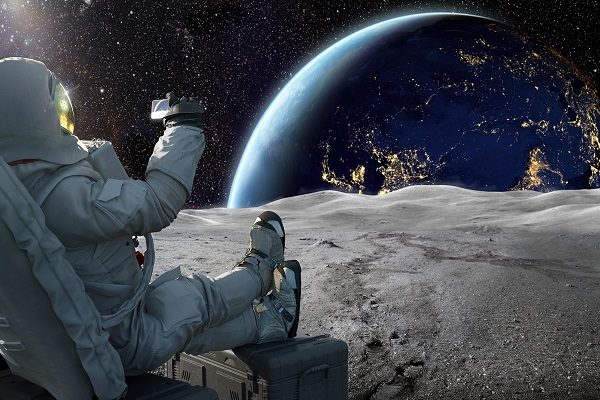 Astronaut Sitting On Moon Recording Sunrise On Earth With Smartphone