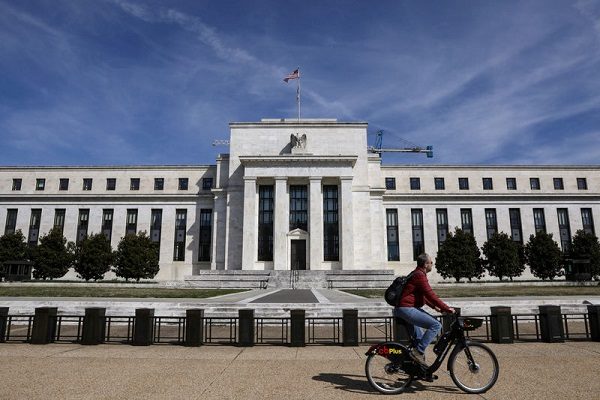 FILE PHOTO: A man rides a bike in front of the Federal Reserve Board building on Constitution Avenue in Washington